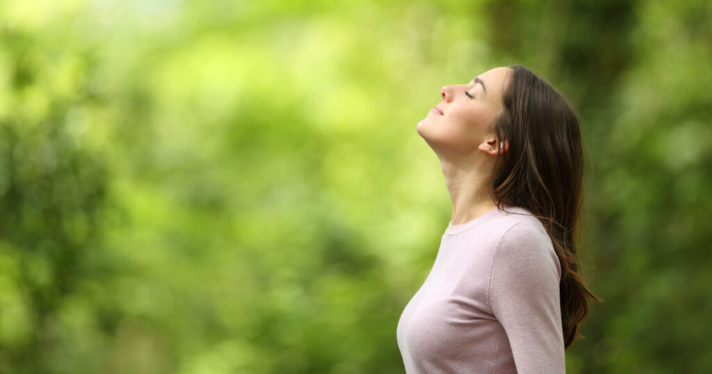 Profile of a relaxed woman breathing fresh air in a green forest