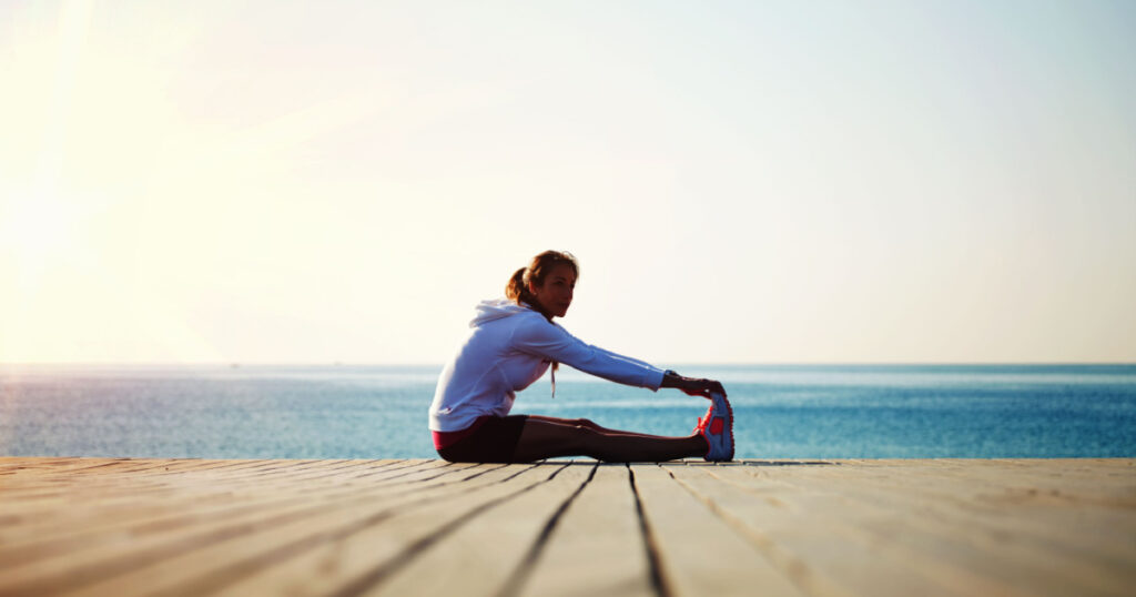 Beautiful female jogger doing workout during the morning training on the beach,workout before the morning jog along the seafront