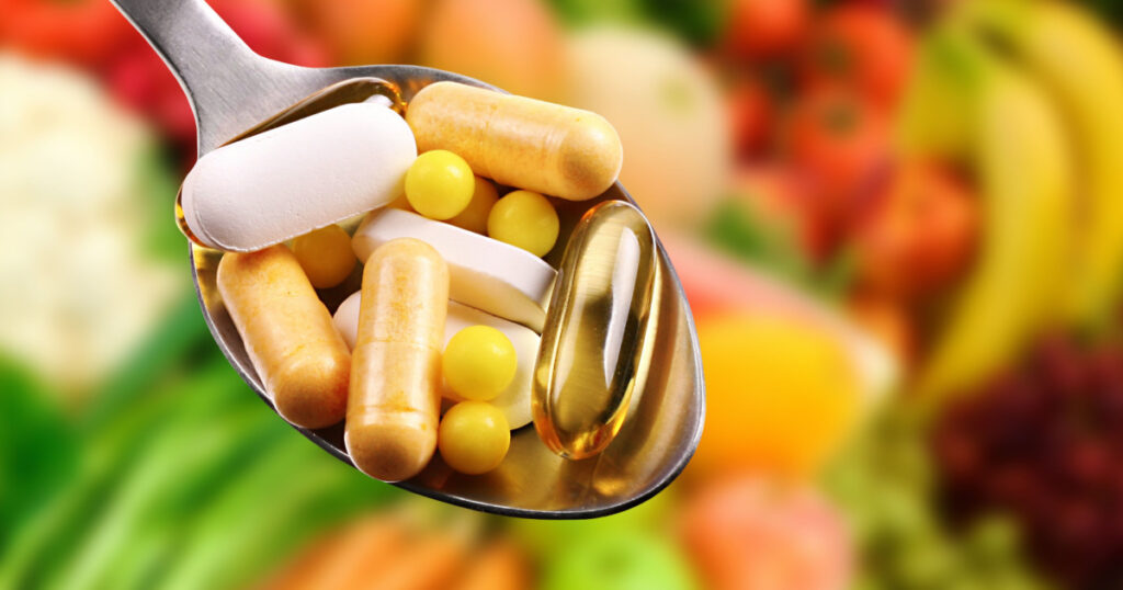 spoon with dietary supplements on fruits background
