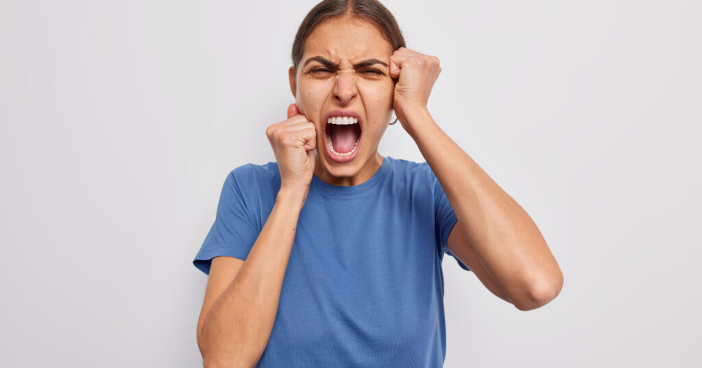 Outraged brunette European woman overreacts on something very bad looks with grief and disappointed as lost someone importan screams from disappointement keeps mouth widely opened frowns face