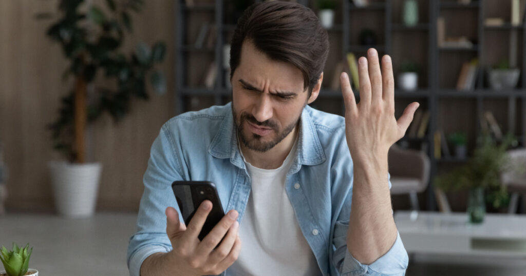 Telephone problem. Upset angry millennial male feel outraged by bad wrong work of smartphone app poor weak wifi signal. Worried nervous young man missed business phone call get too much spam messages