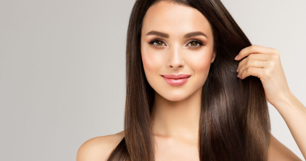 Beautiful model girl with shiny brown and straight long hair . Keratin straightening . Treatment, care and spa procedures. Smooth hairstyle