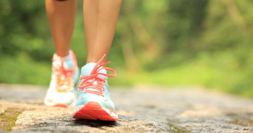 young fitness woman legs walking on forest trail
