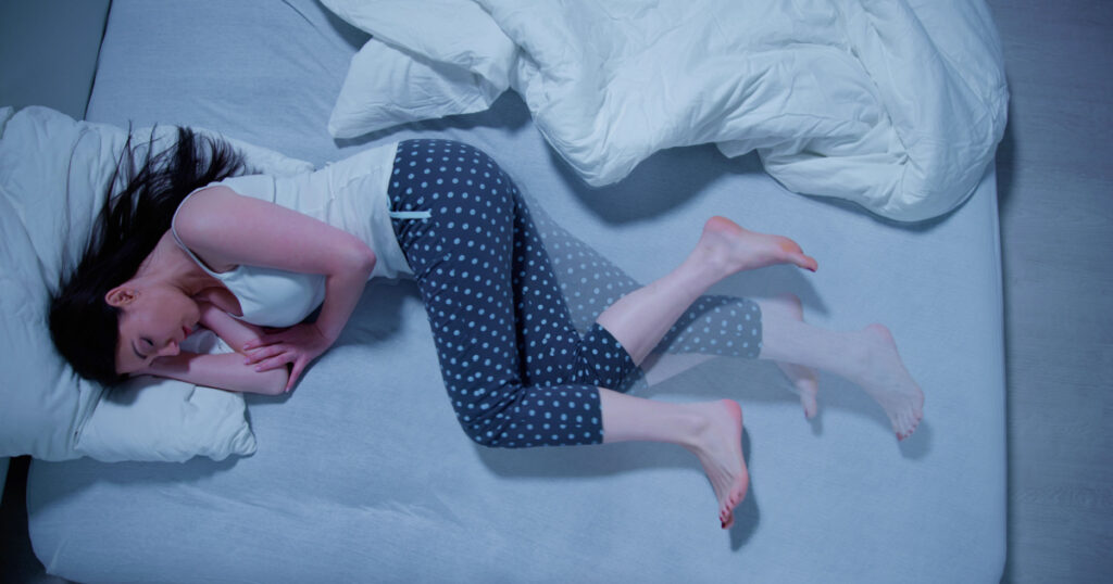 Woman With RLS - Restless Legs Syndrome. Sleeping In Bed