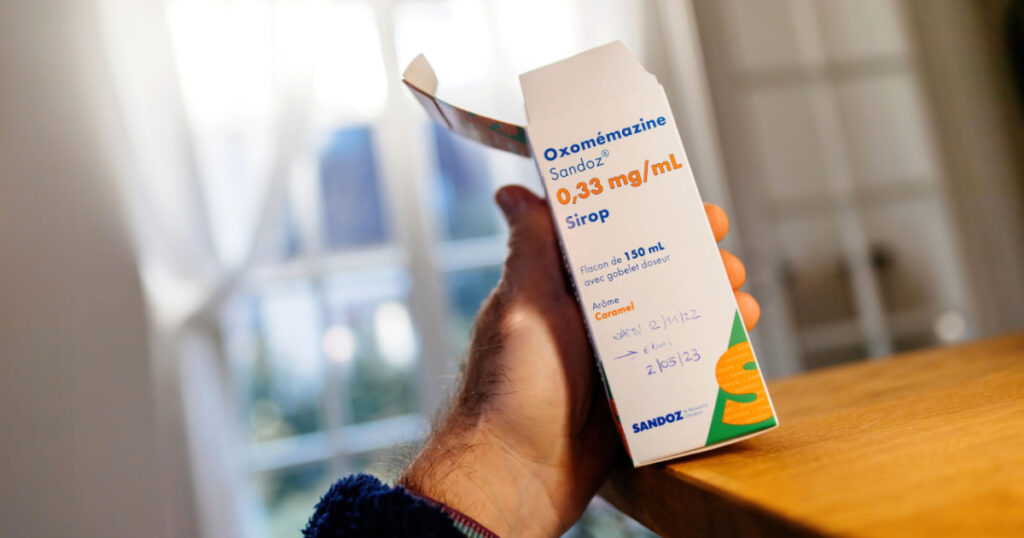Paris, France - Feb 8, 2023: POV male hand holding Oxomemazine pack an antihistamine and anticholinergic of the phenothiazine chemical class for the treatment of cough.