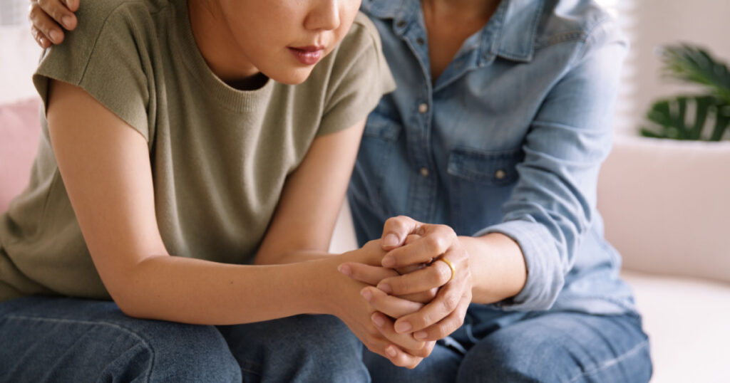 Middle aged asia people old mom holding hands trust comfort help young woman talk crying stress relief at home. Mum as friend love care hold hand adult child feel pain sad worry of life crisis issues.