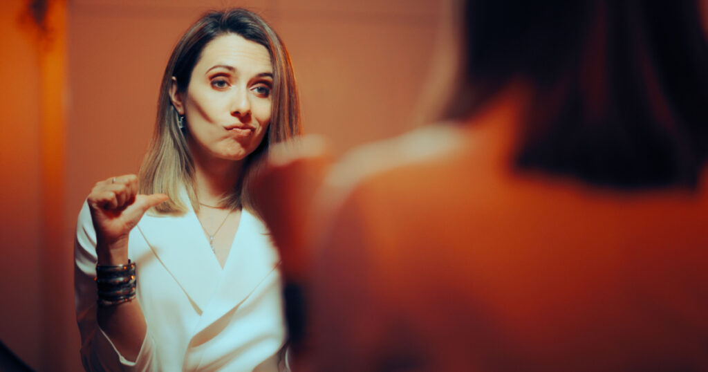 Vain Woman pointing to Herself Looking in the Mirror. Smug Businesswoman thinking in a vain way about herself being narcissistic and overconfident
