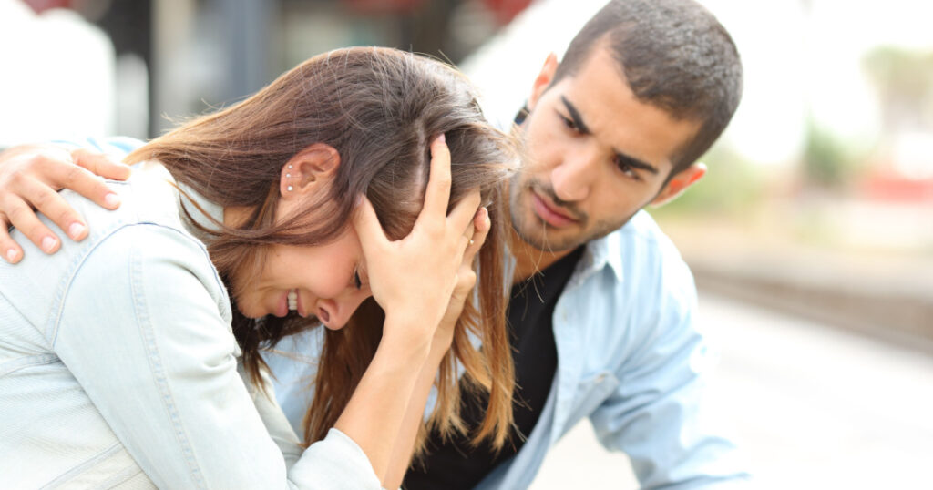 Side view of a muslim man comforting a sad caucasian girl mourning in a train station