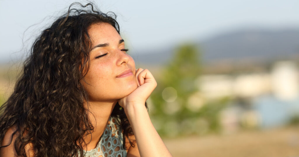 Woman relaxing and enjoying the sun in a warmth park at sunset