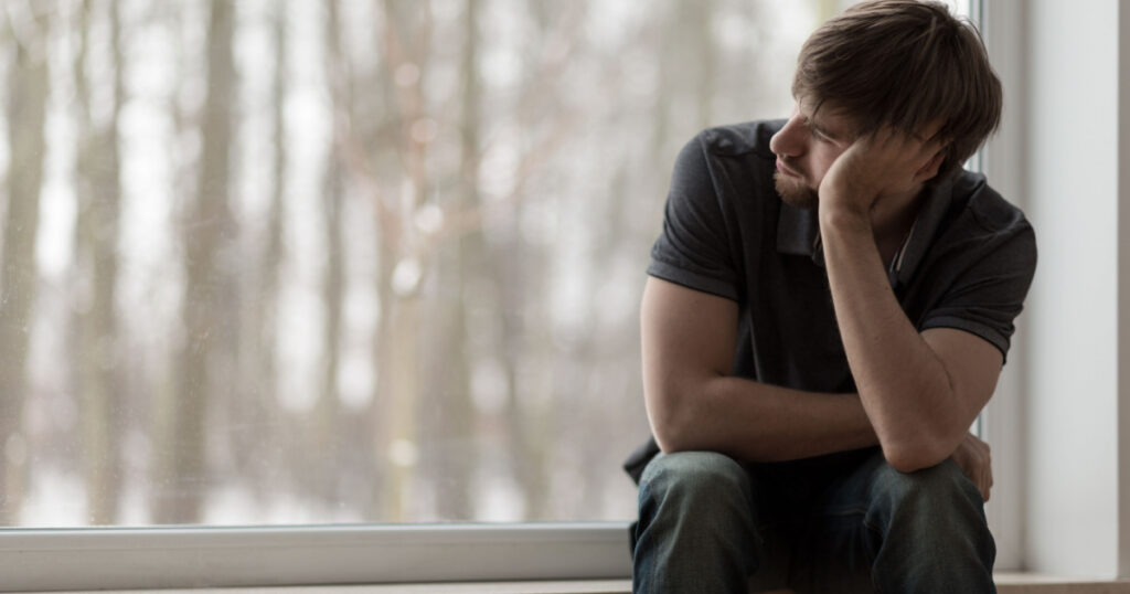 Young miserable depressed man sitting and thinking