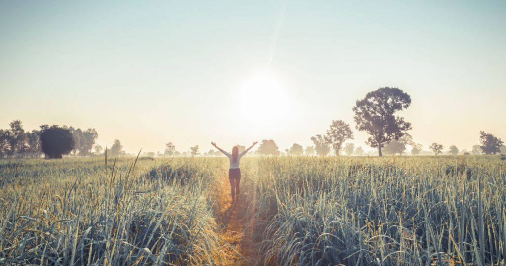 Women enjoying nature in meadow. Outstretched arms fresh morning air summer Field at sunrise.