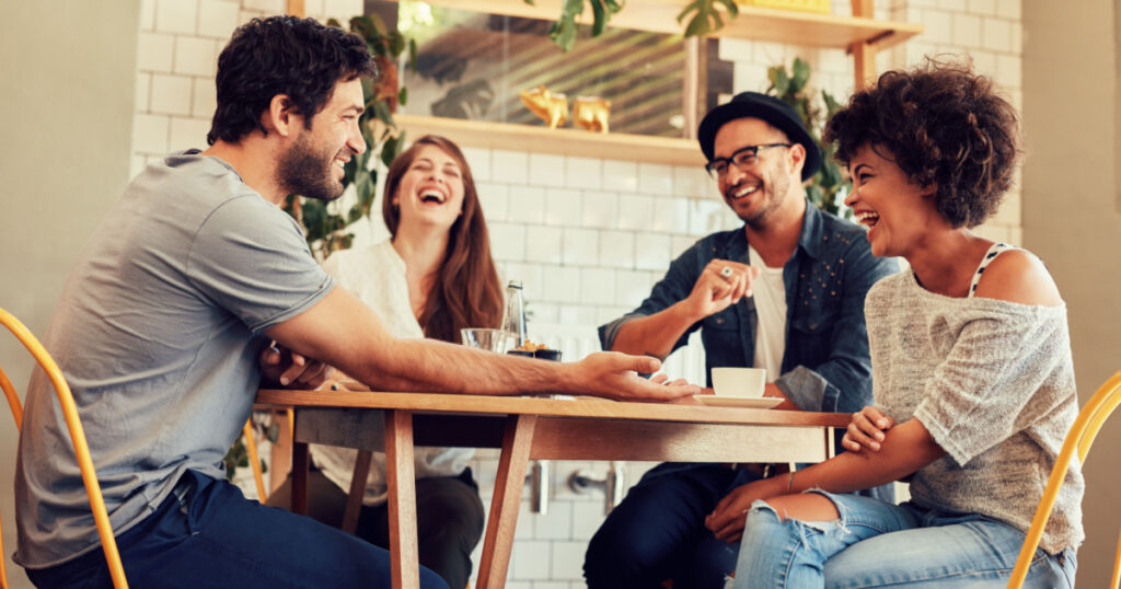 Young friends having a great time in restaurant. Group of young people sitting in a coffee shop and smiling.
