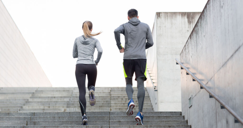 fitness, sport, people, exercising and lifestyle concept - couple running upstairs on city stairs