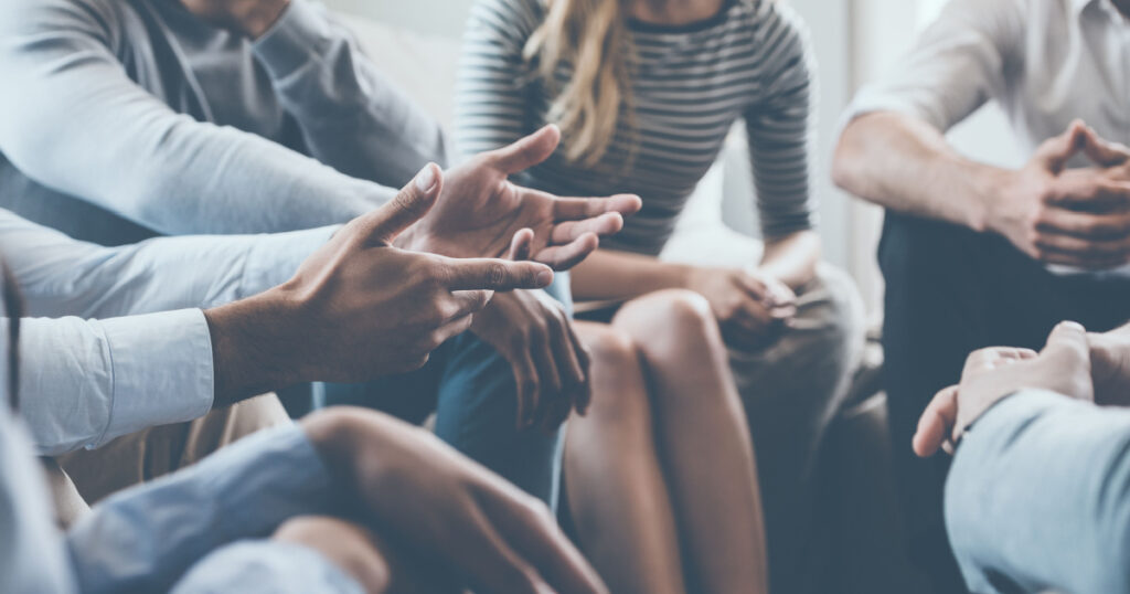 Close-up on discussion. Close-up of people communicating while sitting in circle and gesturing