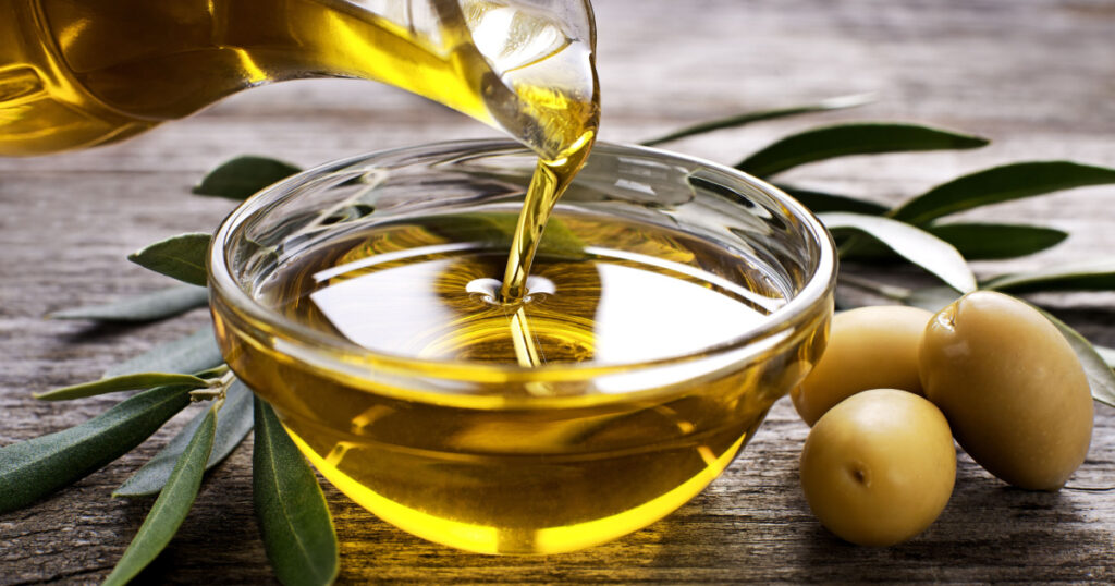 Bottle pouring virgin olive oil in a bowl close up