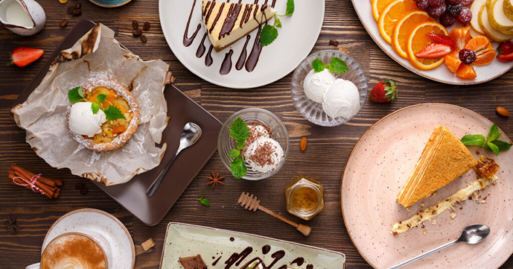 Different desserts with fruits and coffee, top view