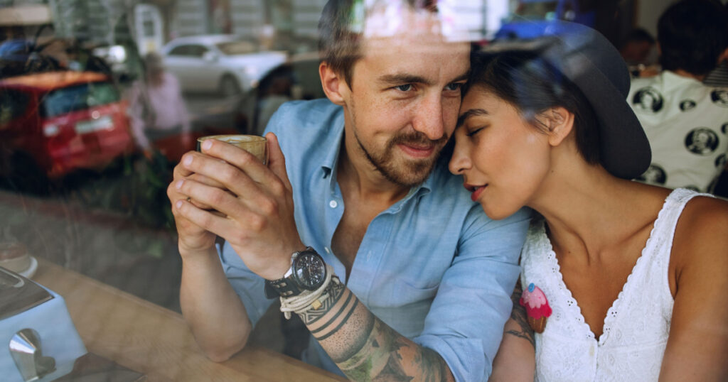 Dreamy couple resting in cafe behind the window at sunny day