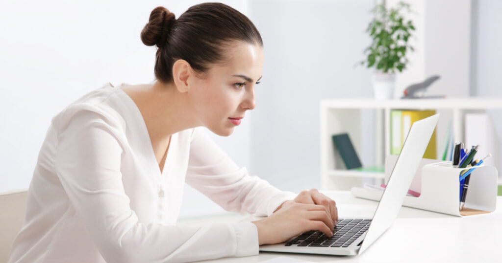 Incorrect posture concept. Young woman sitting at table in modern room