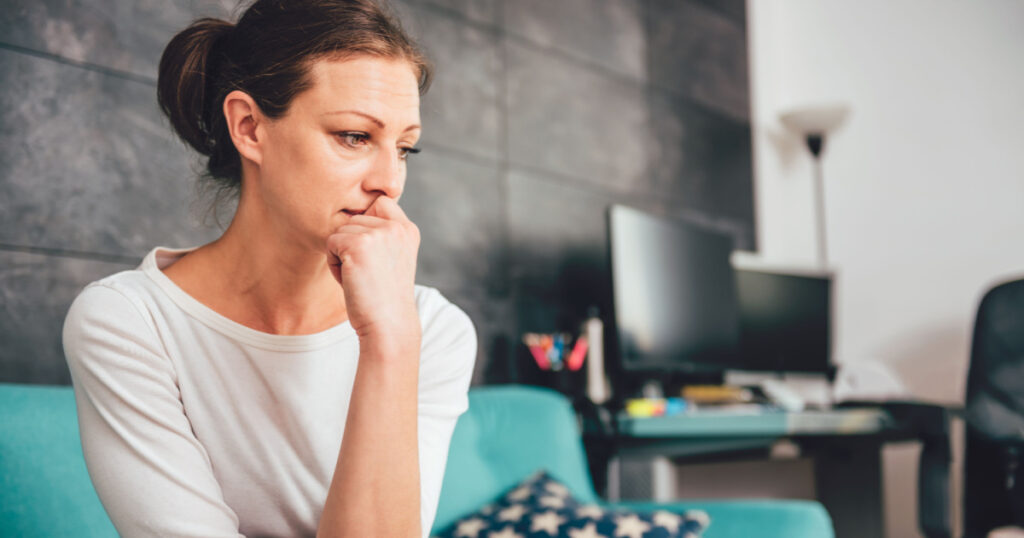 Sad woman sitting on a sofa in the living room