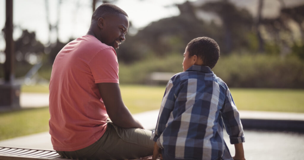 Smiling father talking to son near pool side