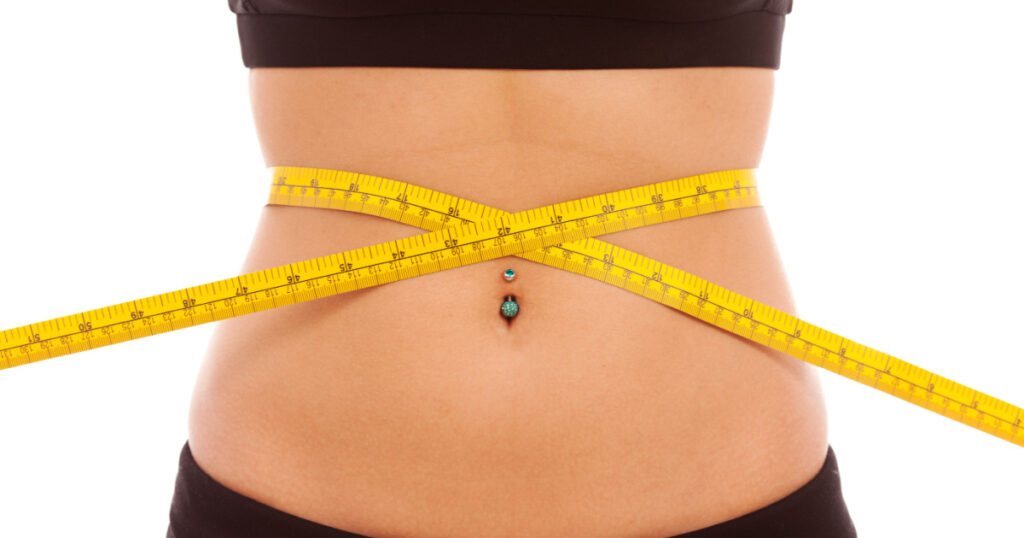 A yellow tape measure around a young females waist