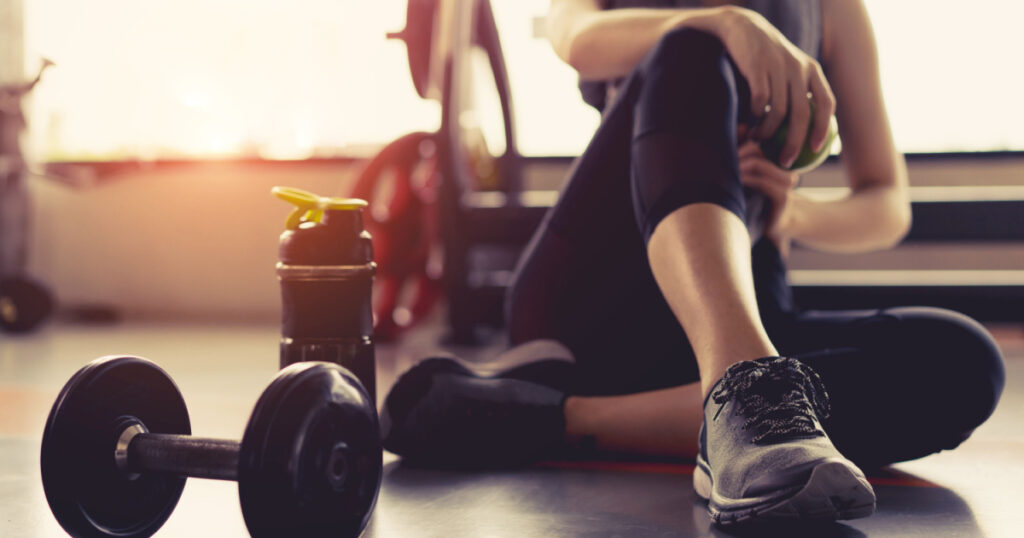 Woman exercise workout in gym fitness breaking relax holding apple fruit after training sport with dumbbell and protein shake bottle healthy lifestyle bodybuilding, Athlete builder muscles lifestyle.