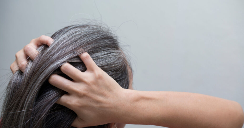woman is checking white hair white looking at the mirror
