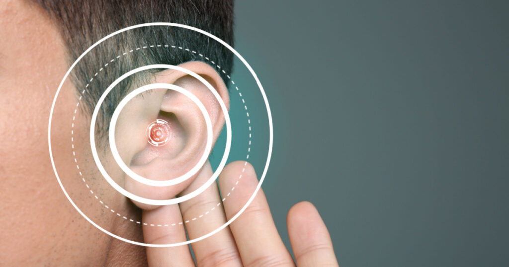 Young man with symptom of hearing loss on color background