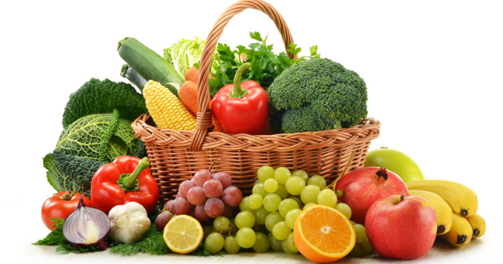 Composition with vegetables and fruits in wicker basket isolated on white