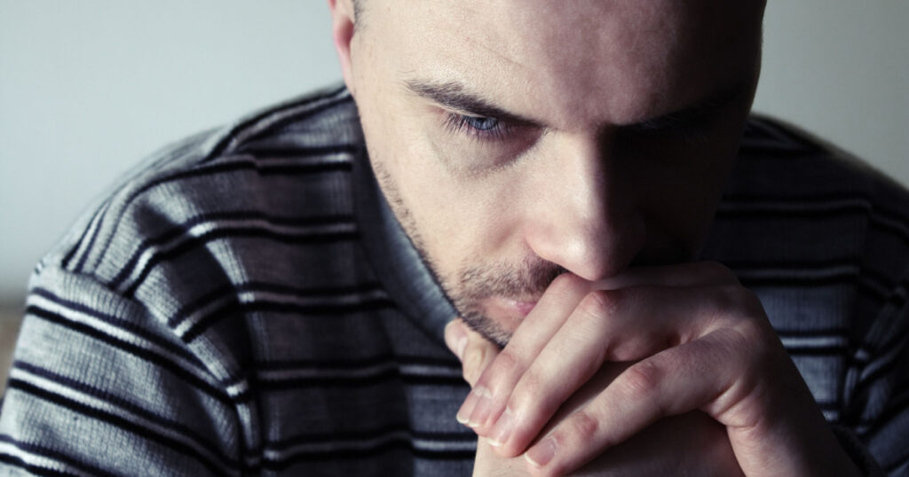 Young man sitting looking upset