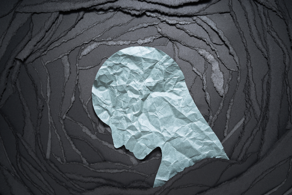 Silhouette of depressed and anxiety person head. Negative emotion image. Person head shaped paper on black torn paper background.

