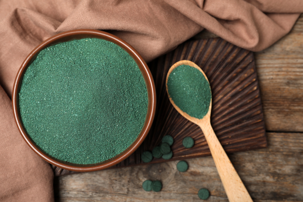 Flat lay composition with spirulina algae powder on wooden background
