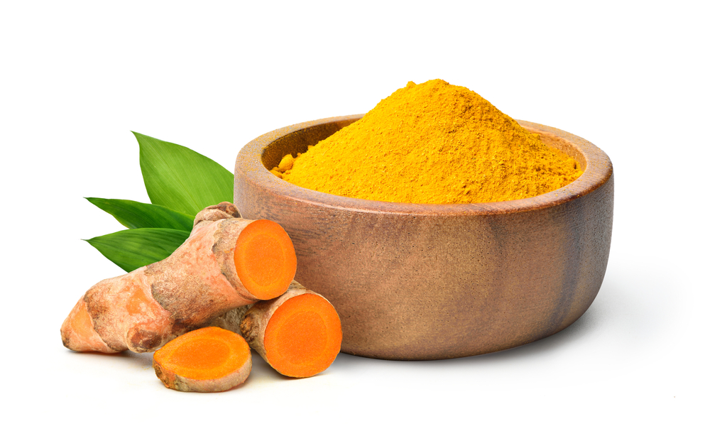 Finely dry Turmeric (Curcuma longa Linn) powder in wooden bow with rhizome (root) sliced isolated on white background.