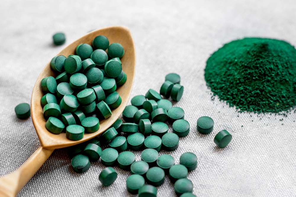 Green seaweed spirulina in tablets and powder on a burlap background. Vegetable protein
