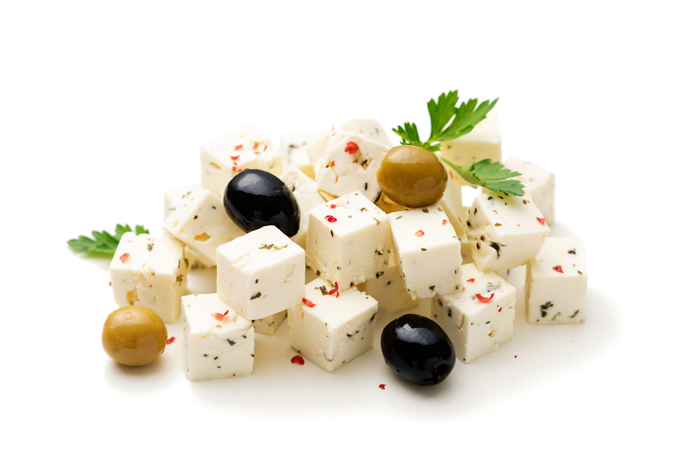 Feta cheese cubes with herbs and olives isolated on white background
