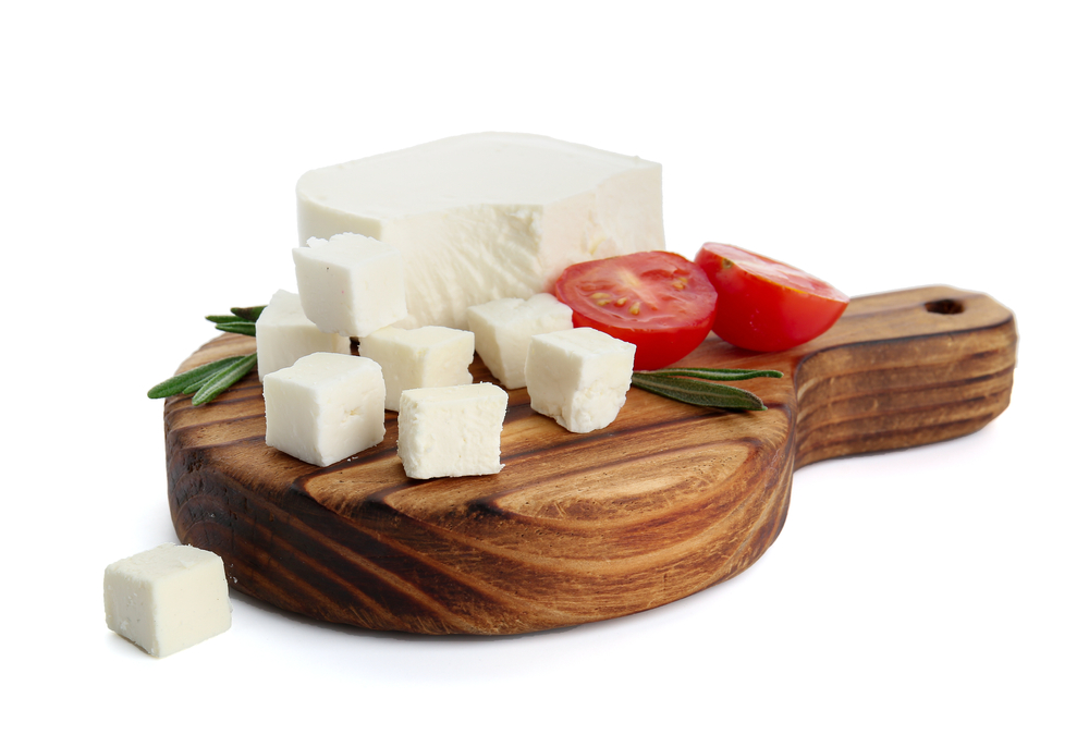Board with tasty cut feta cheese on white background
