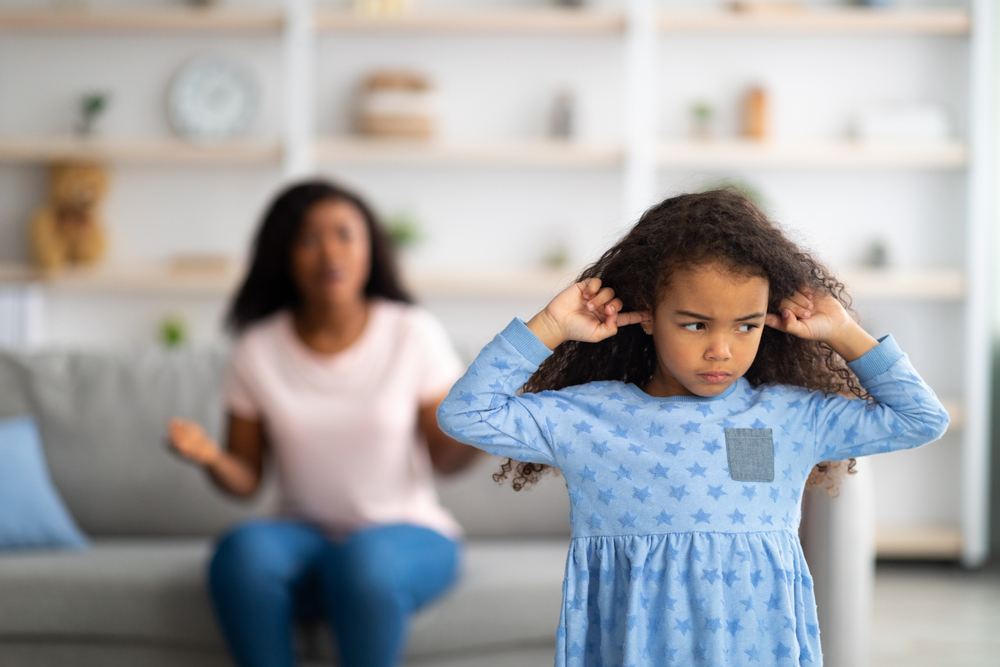 Family argument. Sad offended black girl covering ears, not wanting to listen to her mother's scloding, free space. Millennial woman having fight with her child, quarelling at home