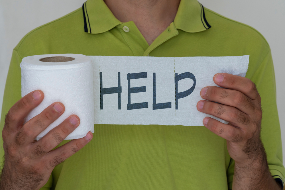 Help written on toilet paper roll in a man's hand. Concept of diarrhea and embarrassment.