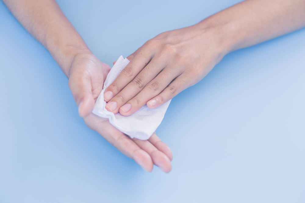 Woman wiping sweat on her hands. Woman suffers from Hyperhidrosis on hand.