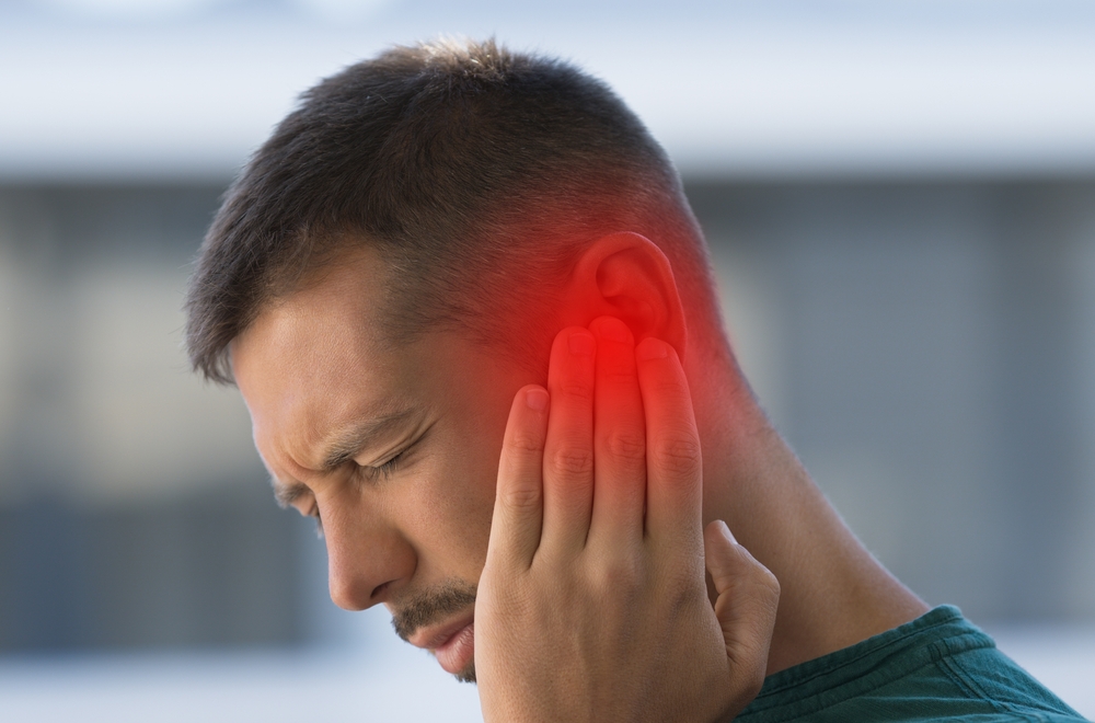 Man suffering from strong earache or ear pain. Ear inflammation, otitis or tinnitus
