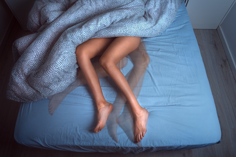 Woman sleeping in the bed and suffering from RLS or restless legs syndrome
