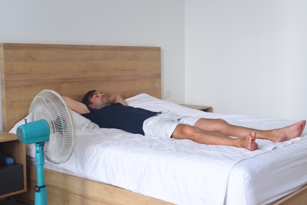 Man sleeping on a bed with fan