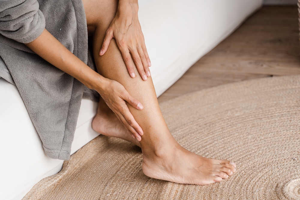 Deep vein thrombosis and varicose of african woman. Girl touching her legs and looking at veins. Sclerotherapy procedure at visiting vascular surgeon doctor