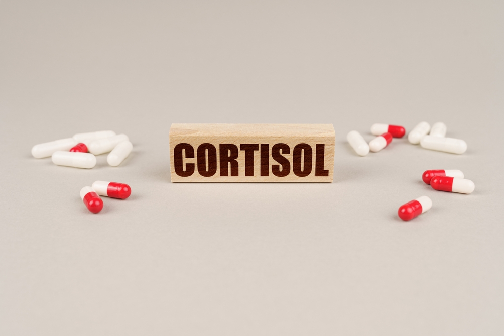 Medical concept. On a gray surface are tablets, capsules and a wooden plate with the inscription - CORTISOL
