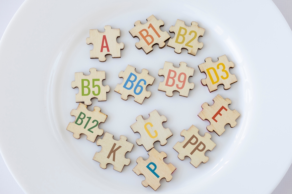 Set of puzzles on plate with 13 essential vitamins with multicolored inscriptions icons. Complex A, B1, B2, B5, B6, B9, B12, C, D3, E, K, P, PP. The concept of healthy eating and health care
