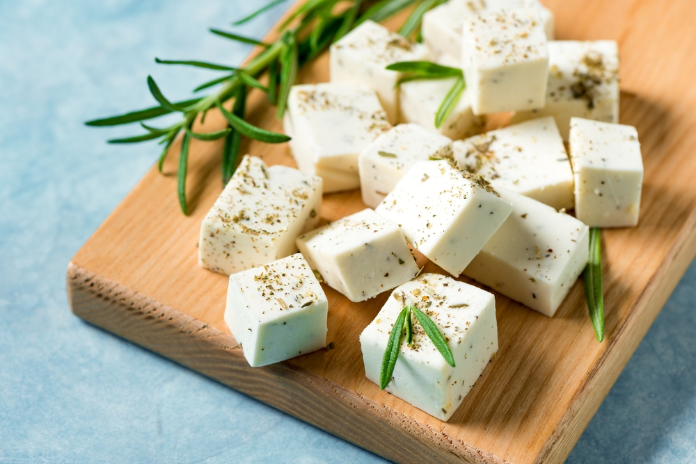 Fresh Greek Feta Cheese. Healthy homemade ingredient for cooking salad. Chopped Goat feta cheese with rosemary herbs close up.
