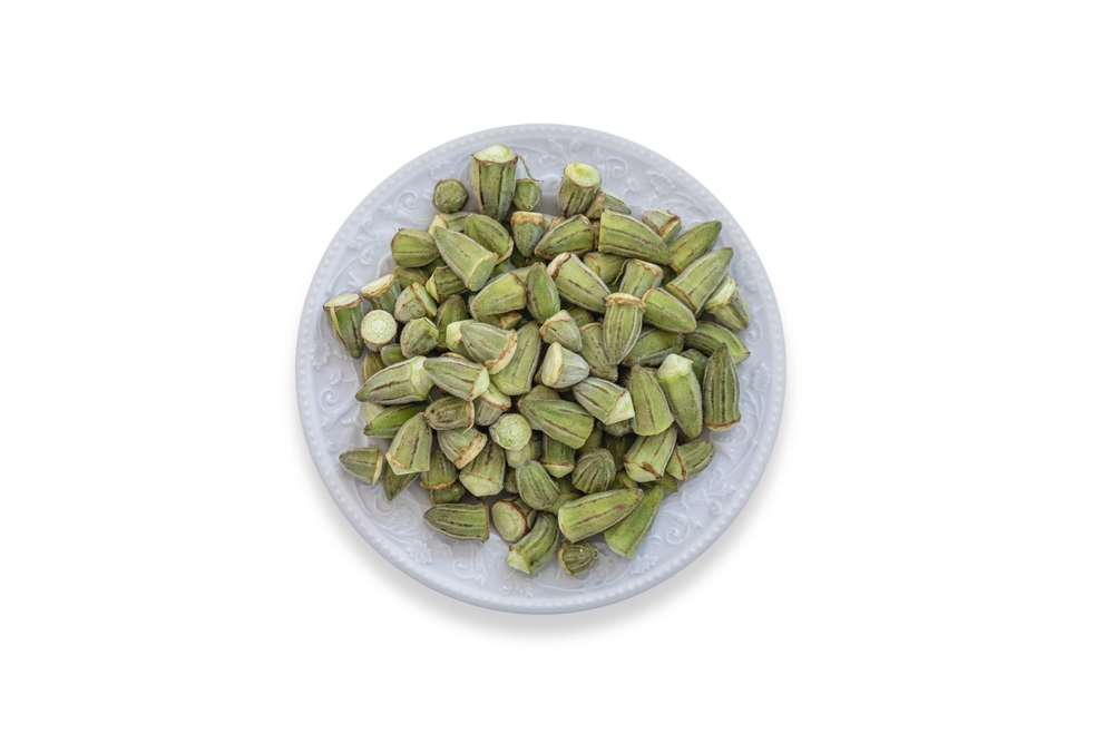 Okra cleaned and prepared for cooking. in a porcelain plate. white background.
