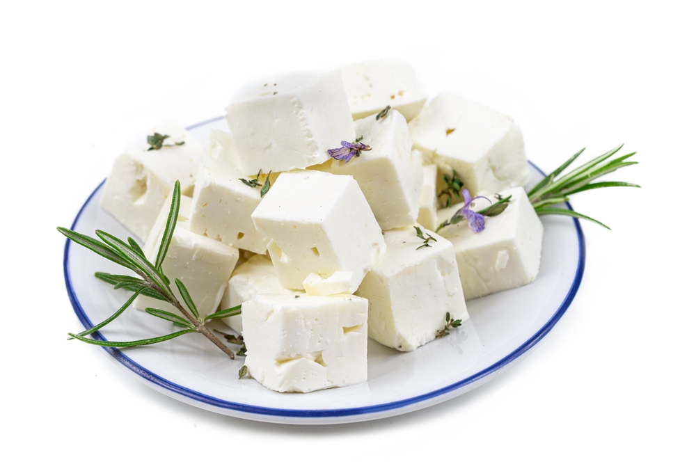 cbes of Feta cheese isolated on white background clipping Heap of Feta cheese, basil leaves and tomatoes.
