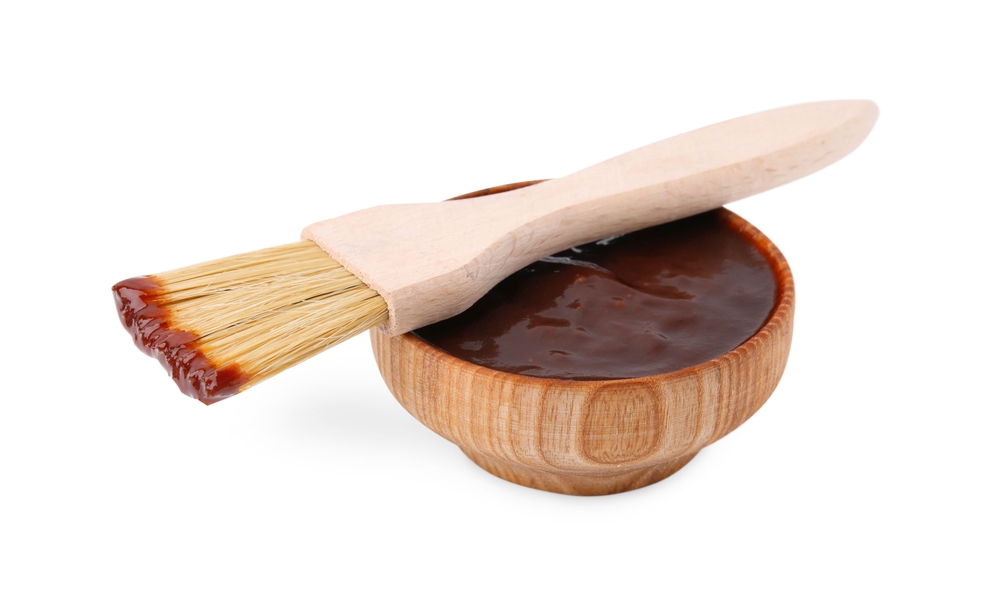 Fresh marinade in bowl and basting brush isolated on white