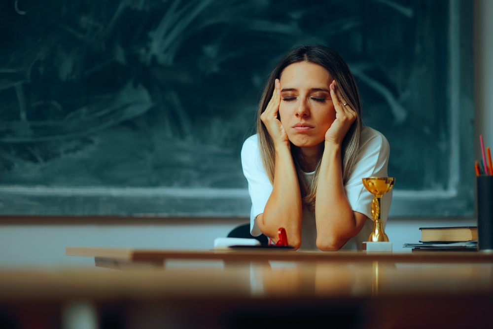 Stressed Teacher Suffering from a Migraine at the Workplace Depressed Anxious professor feeling sick while at work
